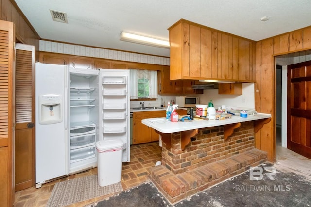 3909 Blue Gill Cir, Mobile, AL 36619 - kitchen with brick patterned flooring, a peninsula, light countertops, wooden walls, and white appliances