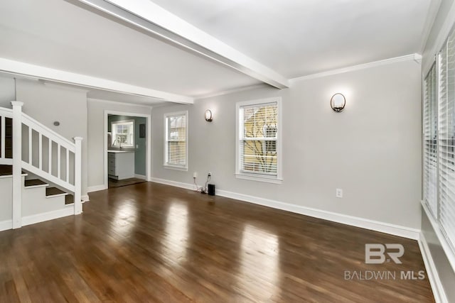 unfurnished living room with beam ceiling, stairway, ornamental molding, wood finished floors, and baseboards