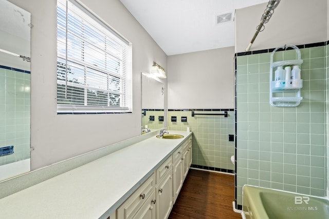 bathroom featuring a tub to relax in, tile walls, vanity, and hardwood / wood-style flooring