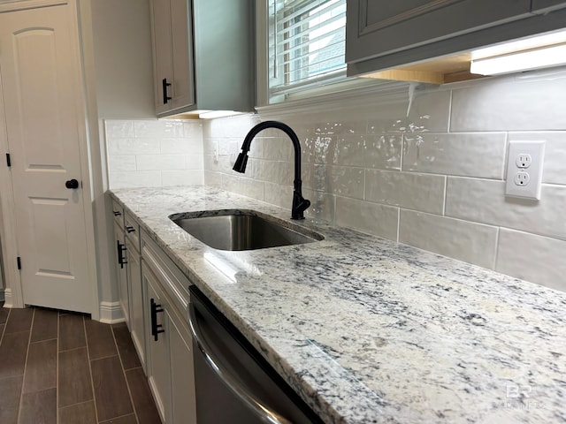 kitchen with light stone countertops, decorative backsplash, dark hardwood / wood-style flooring, gray cabinetry, and sink