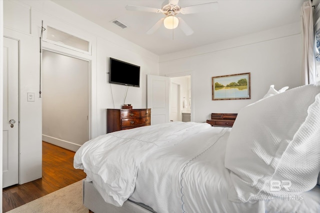 bedroom with wood finished floors, visible vents, ensuite bathroom, and ceiling fan