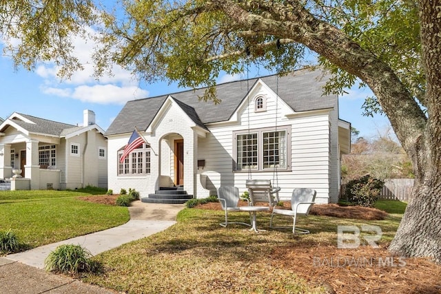 view of front of home with brick siding, a front yard, and fence