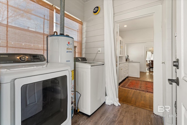 clothes washing area with wooden walls, water heater, laundry area, dark wood-style floors, and separate washer and dryer