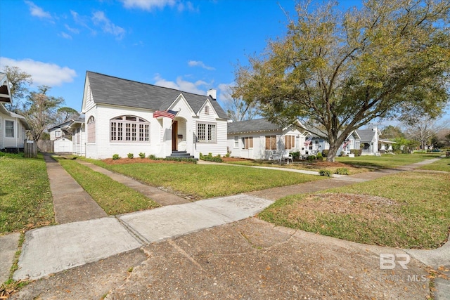 view of front facade with brick siding, a chimney, and a front lawn