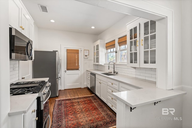 kitchen featuring visible vents, appliances with stainless steel finishes, wood finished floors, white cabinetry, and a sink