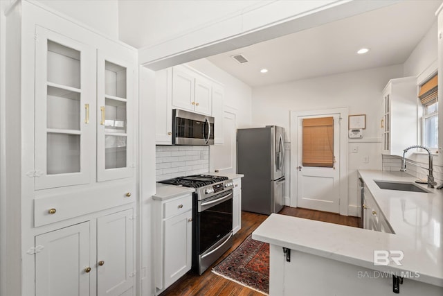 kitchen with visible vents, dark wood finished floors, a sink, white cabinets, and appliances with stainless steel finishes