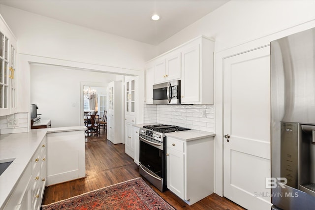 kitchen with tasteful backsplash, appliances with stainless steel finishes, dark wood-style flooring, and white cabinetry