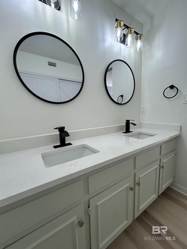 full bathroom with wood finished floors, a sink, visible vents, and double vanity