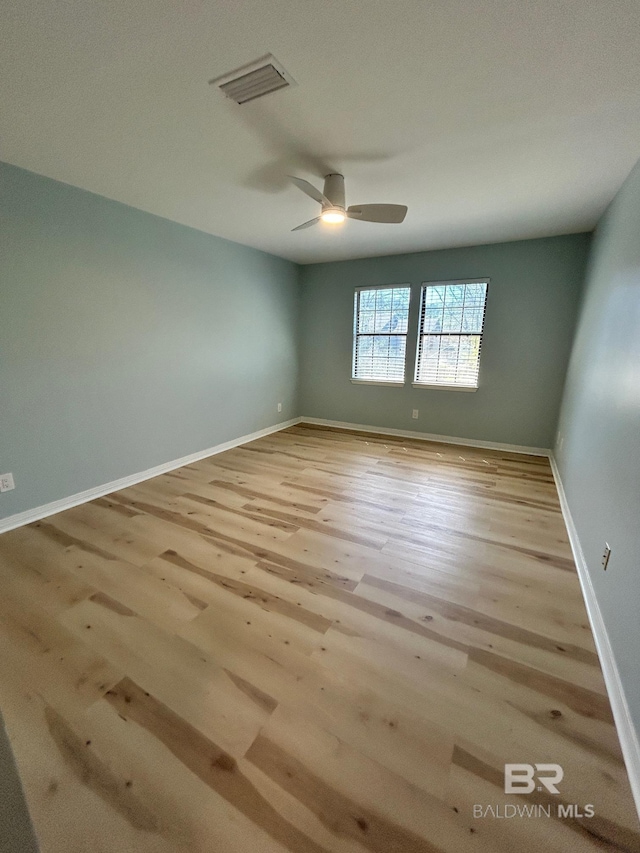 unfurnished room with baseboards, a ceiling fan, wood finished floors, and visible vents