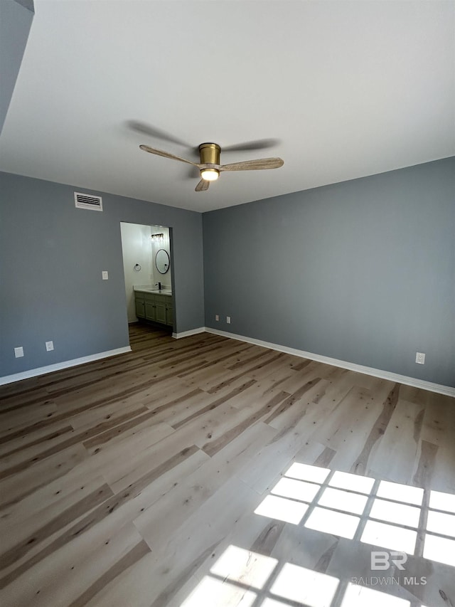 unfurnished bedroom with wood finished floors, visible vents, baseboards, and ceiling fan