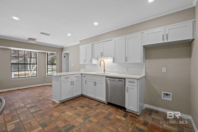 kitchen featuring visible vents, stainless steel dishwasher, a sink, a peninsula, and baseboards