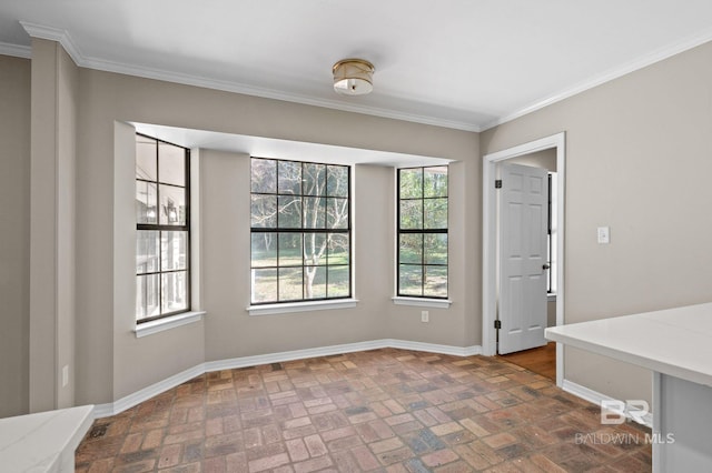 unfurnished dining area with ornamental molding, brick floor, and baseboards