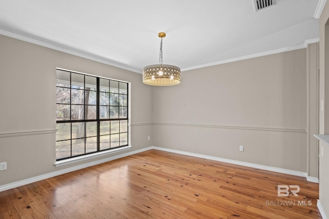 empty room with crown molding, a notable chandelier, visible vents, hardwood / wood-style floors, and baseboards