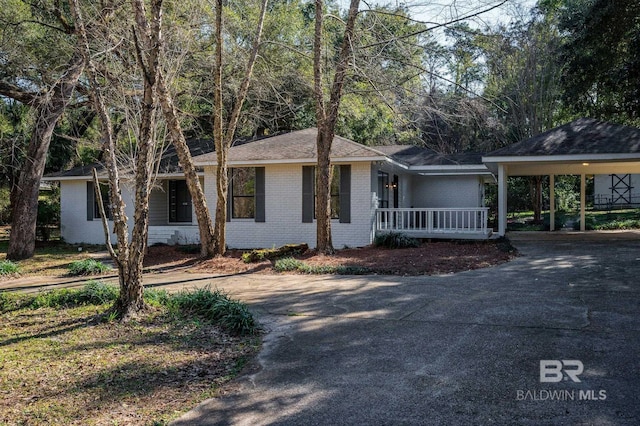 ranch-style home featuring a carport, driveway, brick siding, and a porch