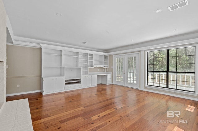 unfurnished living room featuring hardwood / wood-style flooring, baseboards, visible vents, and french doors