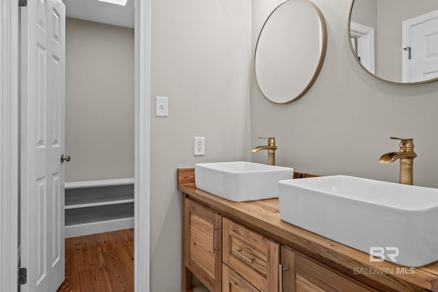 bathroom featuring double vanity, a sink, and wood finished floors