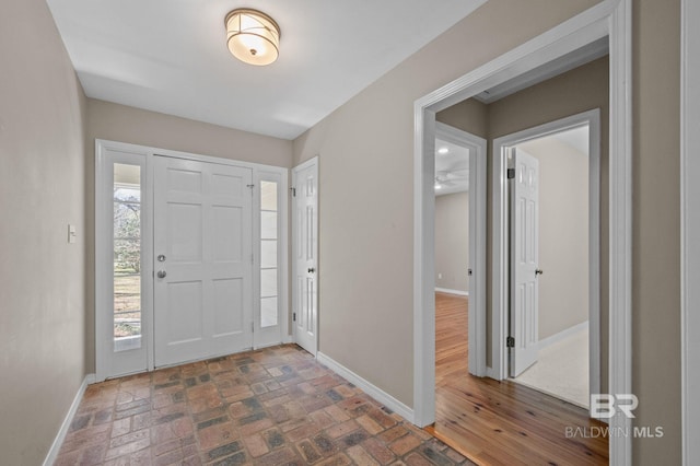 entrance foyer featuring brick floor, plenty of natural light, and baseboards