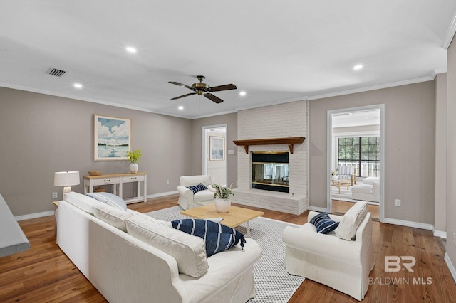 living room featuring ornamental molding, a fireplace, and wood finished floors