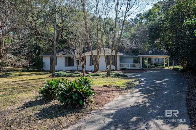 ranch-style home with driveway, an attached carport, and a front yard