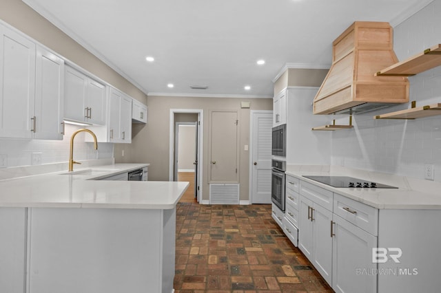 kitchen featuring brick floor, a peninsula, a sink, appliances with stainless steel finishes, and open shelves