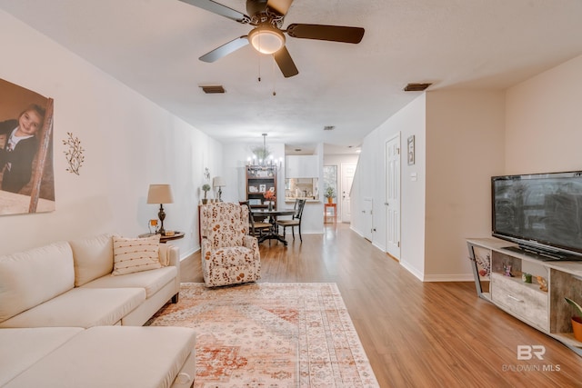 living room with ceiling fan with notable chandelier and light wood-type flooring