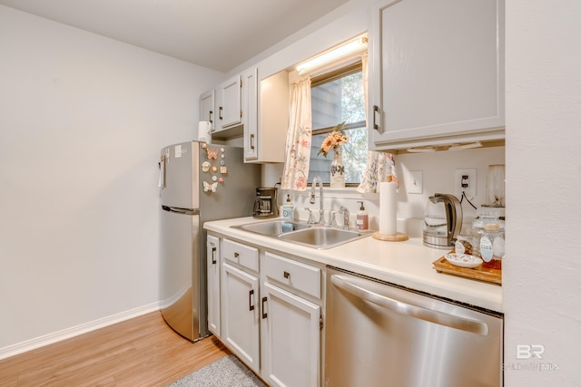 kitchen with white cabinets, sink, light wood-type flooring, and stainless steel appliances