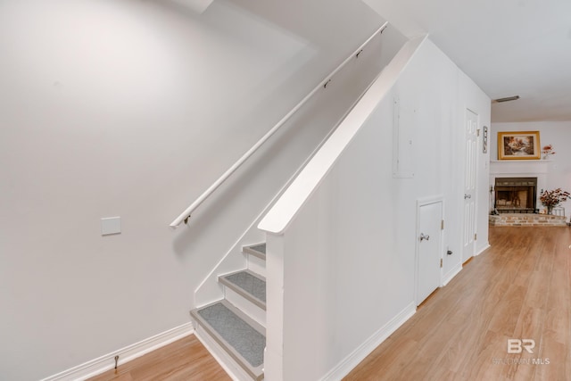 staircase with a brick fireplace and hardwood / wood-style flooring