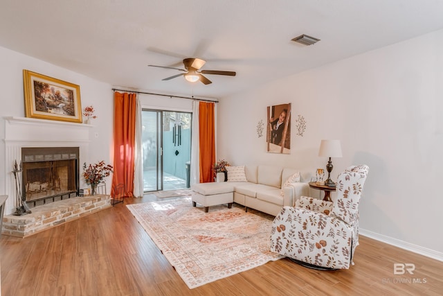 living room with ceiling fan, wood-type flooring, and a fireplace