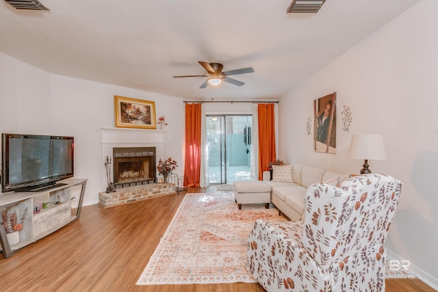 living room with a brick fireplace, ceiling fan, and hardwood / wood-style flooring