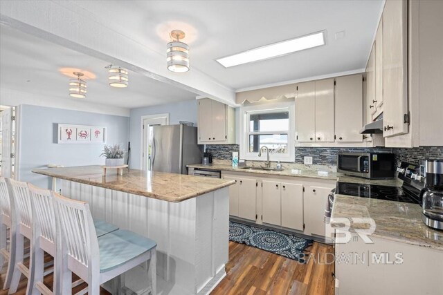 108 Ponchartrain Ct, Dauphin Island, AL 36528 - kitchen featuring stainless steel appliances, decorative backsplash, dark wood-style floors, light stone counters, and a kitchen bar