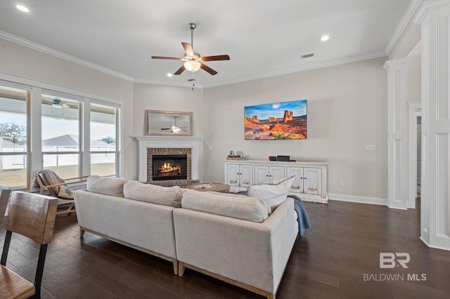 living room with a fireplace, dark wood-type flooring, ornate columns, and ornamental molding