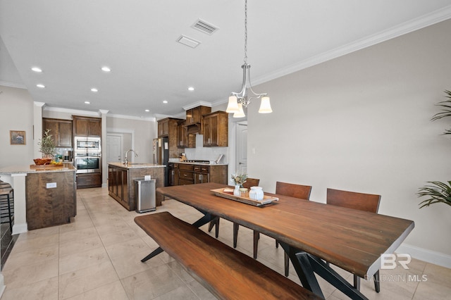 dining area with sink, an inviting chandelier, light tile patterned floors, and ornamental molding