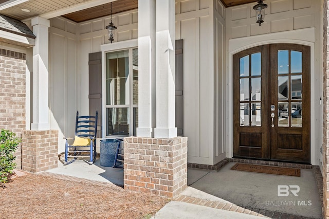 view of exterior entry featuring french doors and covered porch