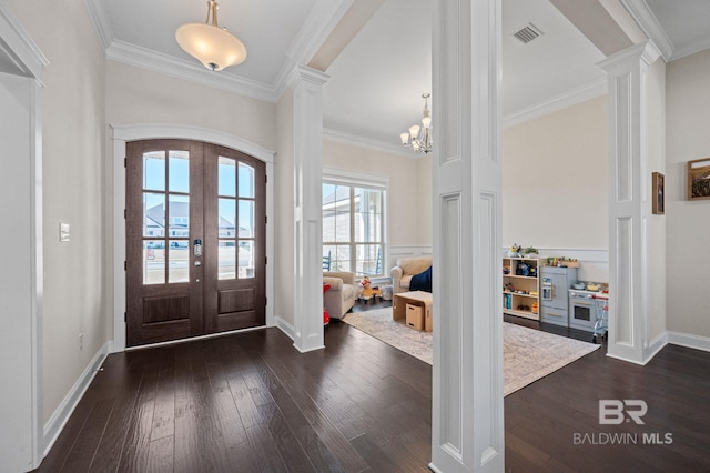 foyer featuring ornate columns, french doors, dark hardwood / wood-style floors, a notable chandelier, and crown molding