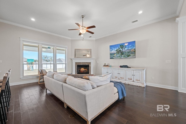 living room with dark wood-type flooring, ceiling fan, and crown molding