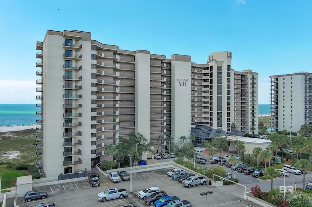 view of apartment building / complex with uncovered parking and a water view