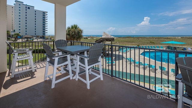 balcony featuring view of pool area, outdoor dining space, and a water view