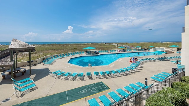 community pool with shuffleboard, a water view, and a gazebo