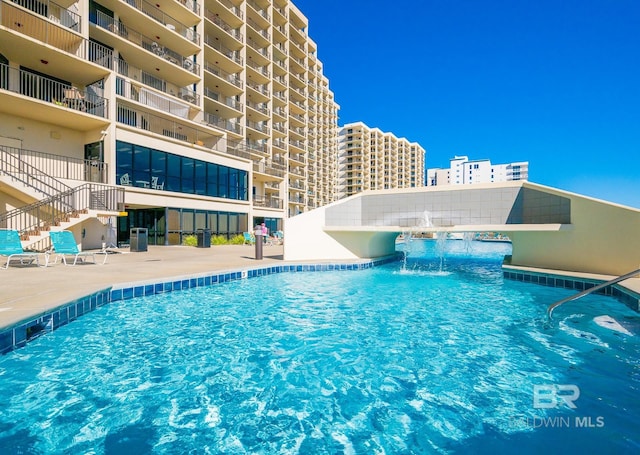 community pool with stairway and a patio area