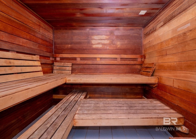 sauna with wooden walls, wood ceiling, and tile patterned flooring