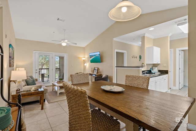 dining space with ceiling fan, light tile patterned flooring, ornamental molding, and vaulted ceiling