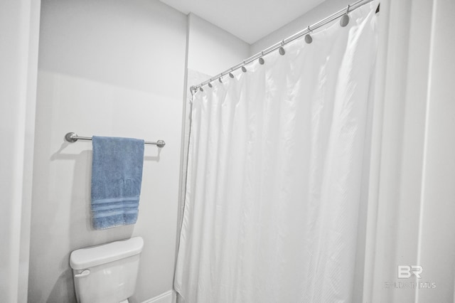 bathroom with toilet and a shower with shower curtain