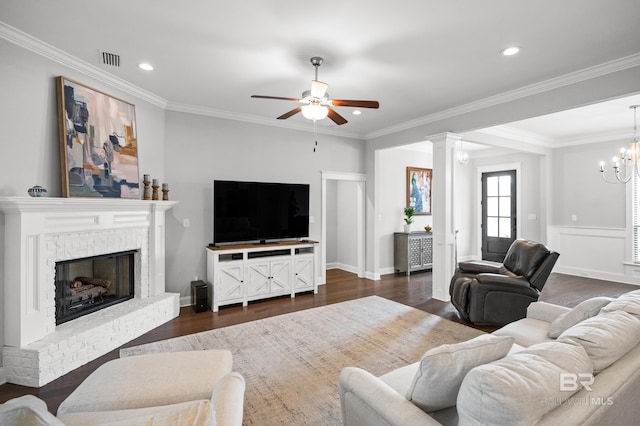 living area with dark wood-type flooring, visible vents, a fireplace, and ornamental molding