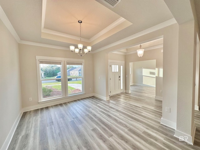 spare room featuring ornamental molding, light hardwood / wood-style flooring, and a raised ceiling