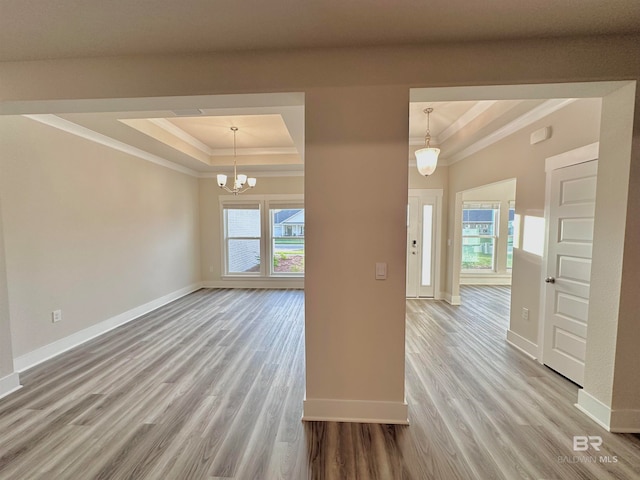 interior space featuring hardwood / wood-style flooring, ornamental molding, a raised ceiling, and a notable chandelier