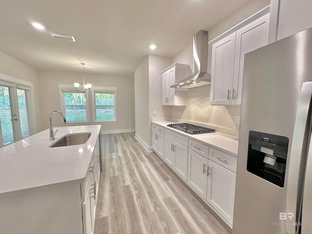 kitchen featuring white cabinetry, an island with sink, sink, appliances with stainless steel finishes, and wall chimney exhaust hood