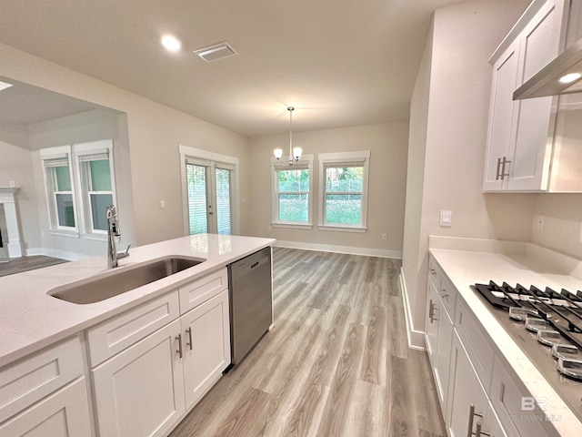 kitchen with stainless steel appliances, white cabinetry, sink, and decorative light fixtures