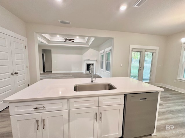 kitchen with sink, stainless steel dishwasher, white cabinets, and a tray ceiling