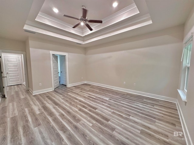 unfurnished bedroom with a tray ceiling, ceiling fan, and light hardwood / wood-style flooring