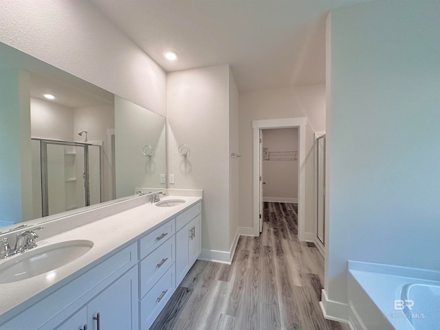 bathroom with wood-type flooring, vanity, and shower with separate bathtub